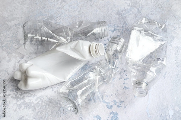 Fototapeta Table top view of crushed plastic bottles prepared for recycle on gray background. Waste sorting and plastic recycle concept