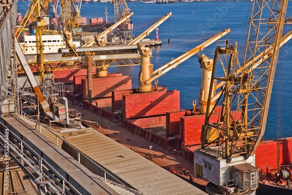 Fototapeta Loading grain into holds of sea cargo vessel in seaport from grain storage.