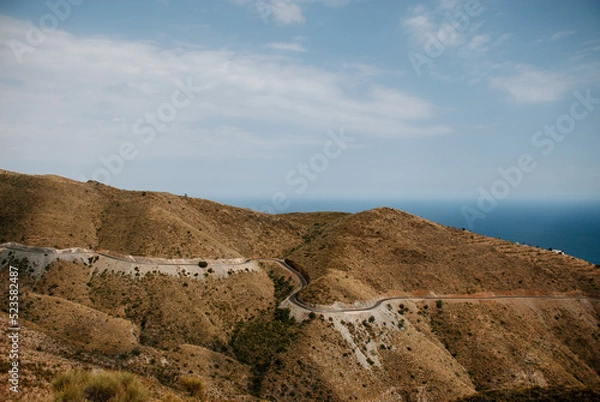 Obraz Landscape with the front view of a mountain, the road with curves and the sea in the background. In Adra, Almeria.