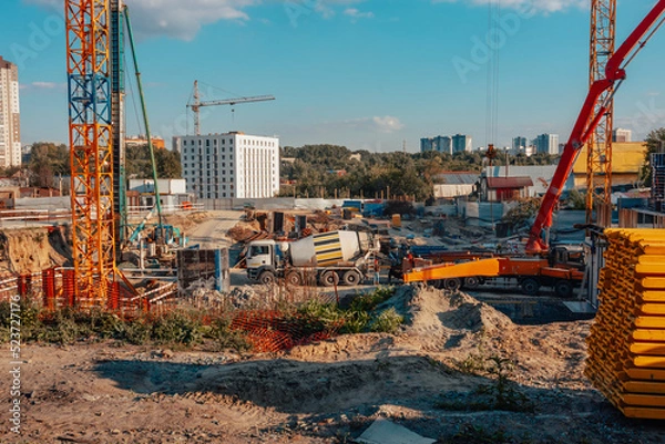 Fototapeta Construction of new houses. Building. Construction site. A car with concrete. Cranes.
