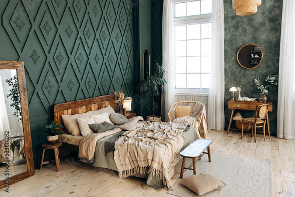 Obraz Cozy boho bedroom with wooden furniture, console table, textiles, green walls, large windows and potted plants. Empty space