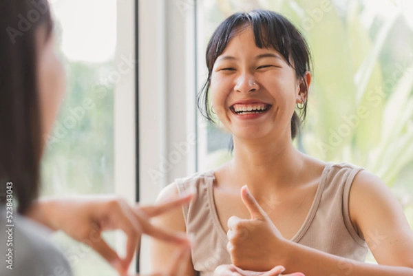 Obraz Young attractive Asian women using sign hand finger language conversation with deaf person. Cheerful happy using nonverbal communication to persons with disabilities.