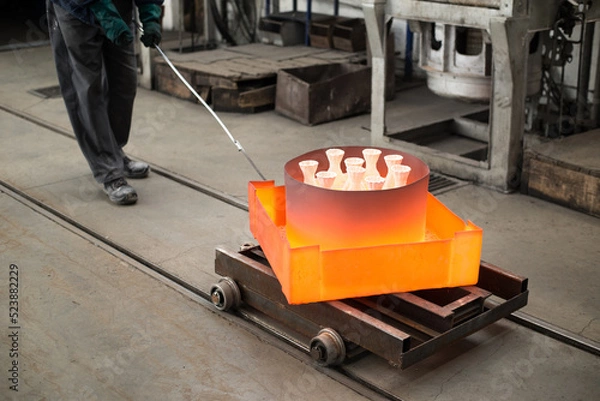 Fototapeta Workers molding objects in the foundry, pouring melted metal in molds