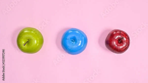Fototapeta Green , red and blue apples on pastel pink background. Creative colorful healthy lifestyle concept. Flat lay minimal