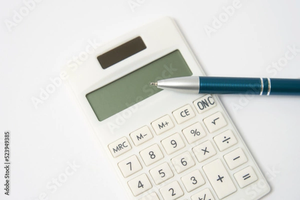 Obraz 白背景にある電卓とボールペンのクローズアップ