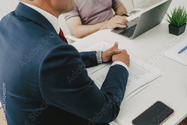 Fototapeta businessman in a meeting brainstorming with other office workers at a table. Closed picture of his hands.