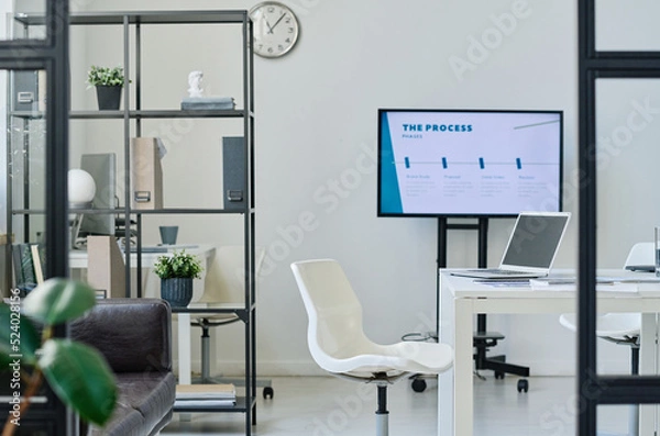 Fototapeta Modern office room with table in the middle and big monitor for meeting and presentation