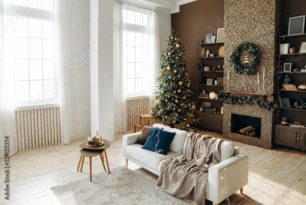 Obraz Classic Christmas interior in the living room with a sofa, brown walls, large windows, fireplace and shelves with decor. Cozy New Year's interior with a Christmas tree and a wreath over the fireplace