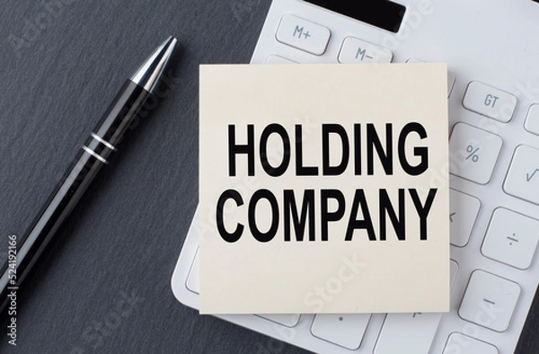 Fototapeta Text HOLDING COMPANY on sticker on calculator, business concept