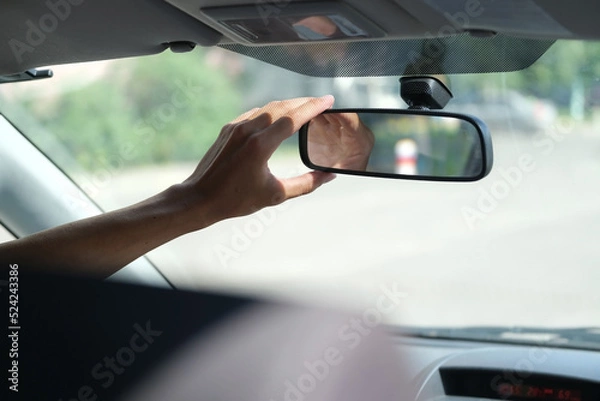 Fototapeta hand of the driver who adjusts the rear view mirror in the car