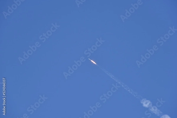 Fototapeta Distant Rocket Launch clear Blue Day with exhaust trail and sunny sky