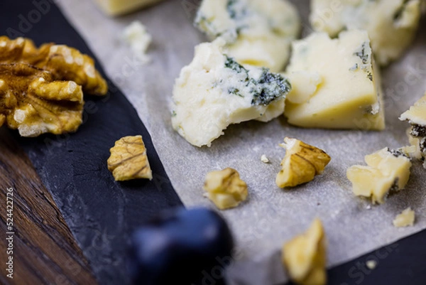 Fototapeta Tasty blue cheese served with grape and green on a wooden background. Dorblu cheese pieces