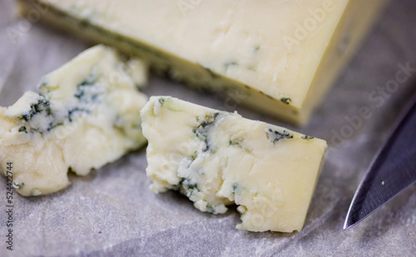 Fototapeta Tasty blue cheese served with grape and green on a wooden background. Dorblu cheese pieces
