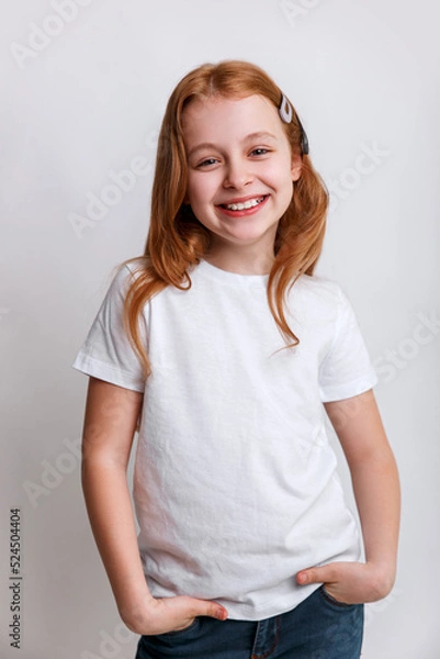 Obraz Redhead smiling little girl model posing in white t-shirt on grey background