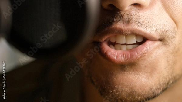 Fototapeta Close up on radio or podcast presenters mouth as he talks into a microphone 