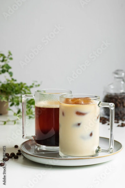 Fototapeta Two cups of coffee. Hot coffee in the background, coffee ice with milk in the foreground (a coffee drink made from ice cubes of coffee). Close-up.