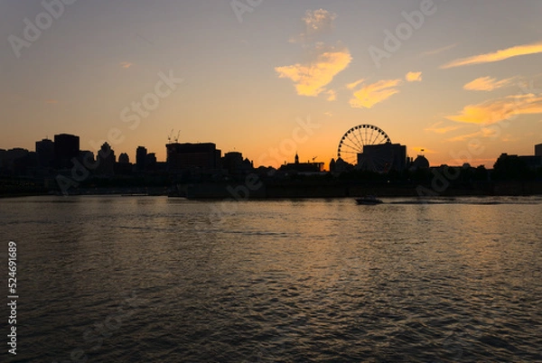 Fototapeta Montreal Downtown skyline at sunset. Reflections of sun rays on Saint Laurent river with a background of cloudy blue sky