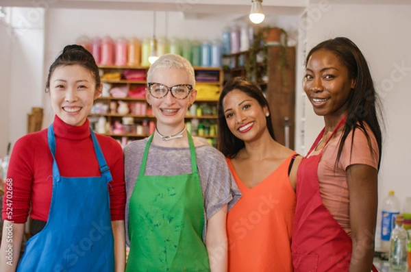 Fototapeta Portrait of four diverse attractive women in an arts and crafts shop smiling to camera 