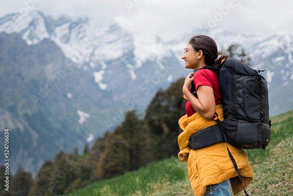 Obraz Teenager Indian girl hiking on mountain with backpack in Manali, Himachal Pradesh, India. Female hiker enjoying idyllic view of Himalayan mountain range. Travel and adventure activity