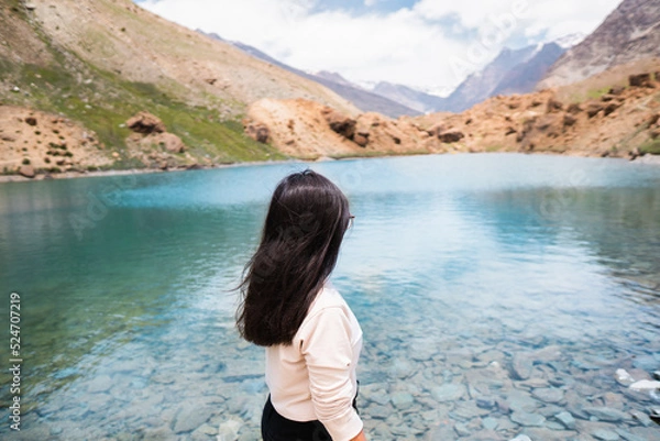 Obraz Seen from behind Beautiful Indian tourist woman standing against Deepak Tal lake in front of Himalayan mountains at Himachal Pradesh, India. Mountain landscape, glacier lake and mountain range