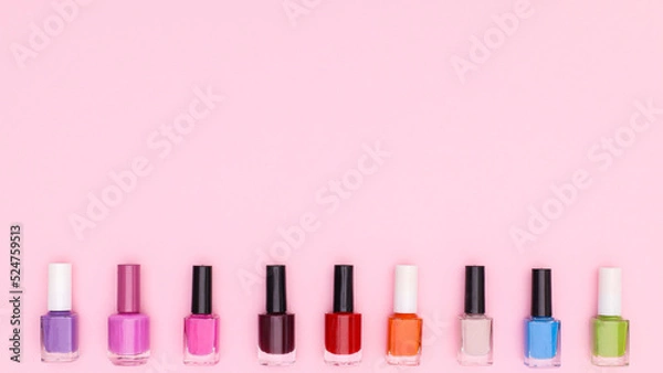Fototapeta Colorful nail polish bottles on pastel pink background. Flat lay copy space