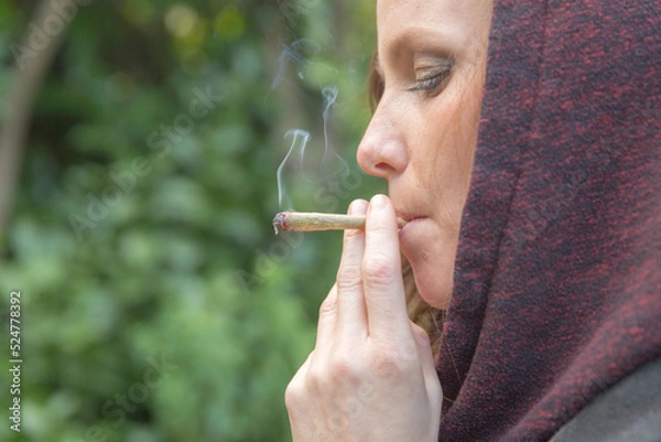 Fototapeta Woman smoking cannabis joint