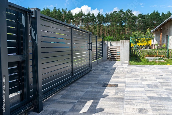 Obraz Modern panel fencing in anthracite color, visible sliding gate to the garage as well as a handle and a lock.
