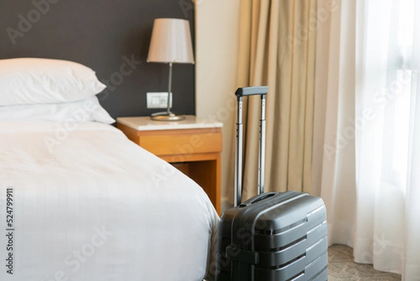 Fototapeta Black travel suitcase in bedroom or hotel room and window curtain background. Relaxing time on holidays, weekend and traveling, business trip concept. Copy space