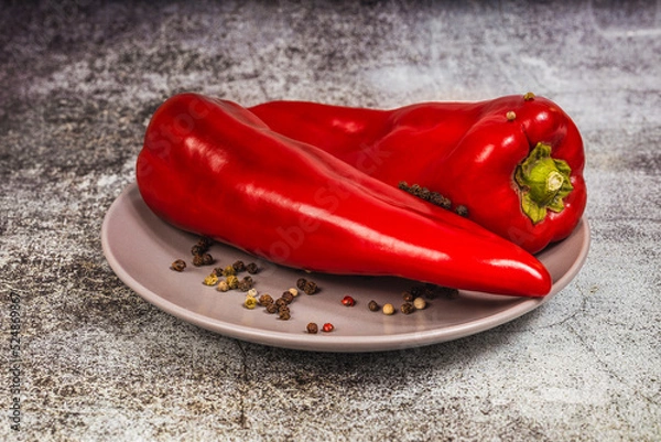 Obraz Two red sweet allspice on a plate on a gray background