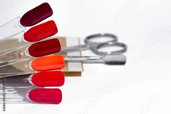 Fototapeta Samples of red gel polish on the background of blurred tools for professional manicure or pedicure with space for text.