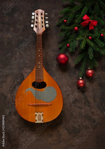 Fototapeta Old mandolin and fir-tree branches with Christmas decor. Christmas and New Year's concept. Top view, close-up on dark concrete background...