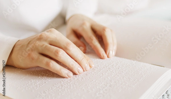 Obraz Poorly seeing woman learning Braille book. A person with blindness touches and reads with his hands.