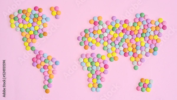 Fototapeta World map made with colorful candies on pastel pink bakcgorund. Flat lay. Concept Earth