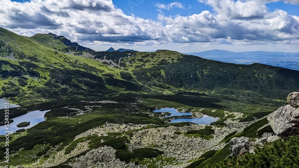 Fototapeta Beautiful landscape of lakes and mountains under the cloudy blue sky as wallpaper, poster or background. Incredible view of lakes and meadow under the mountains in the light of the sun. 