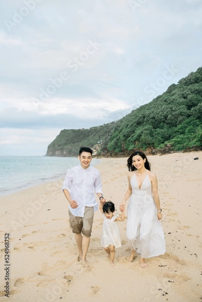 Obraz A small family of three is having fun on the beach under the sun light in the morning