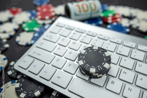 Fototapeta poker chips for poker with banknotes twisted placed on laptop keyboard.