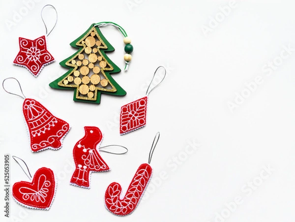 Fototapeta New Year and Christmas hand made red and green decorations made of wood and felt fabric on white paper. Flat lay, copy space