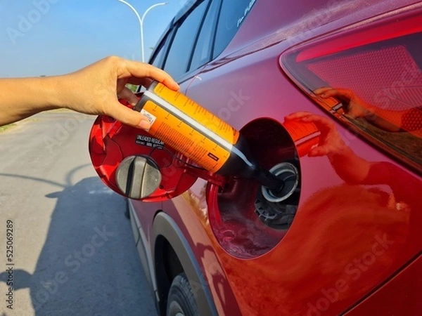 Fototapeta a driver fills a diesel additive into a car's diesel fuel tank to increase the cetane number and lower the sulfur content of biodiesel
