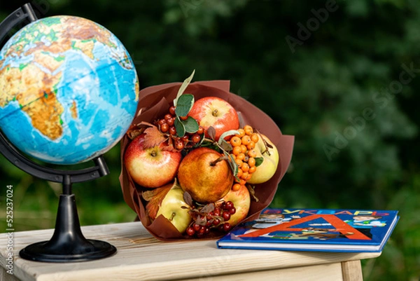 Fototapeta Back to school time. Copy space image for russian Day of Knowledge. Bright autumn image. Globe, fruit bouquet and textbook. Bouquet for teacher. Selective focus.