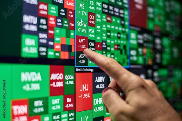 Obraz A trader points his finger at one of the stocks on a stock heatmap