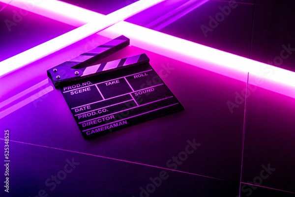 Fototapeta Clapperboard movie slate on Glowing neon lighting background. video director making cinema film. Film clapper design element. filmmaker clapperboard to make video film
