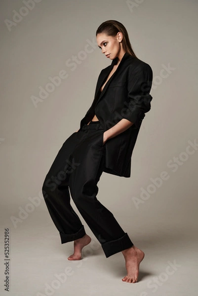 Fototapeta Fashion portrait of a beautiful young woman posing in a black evening suit