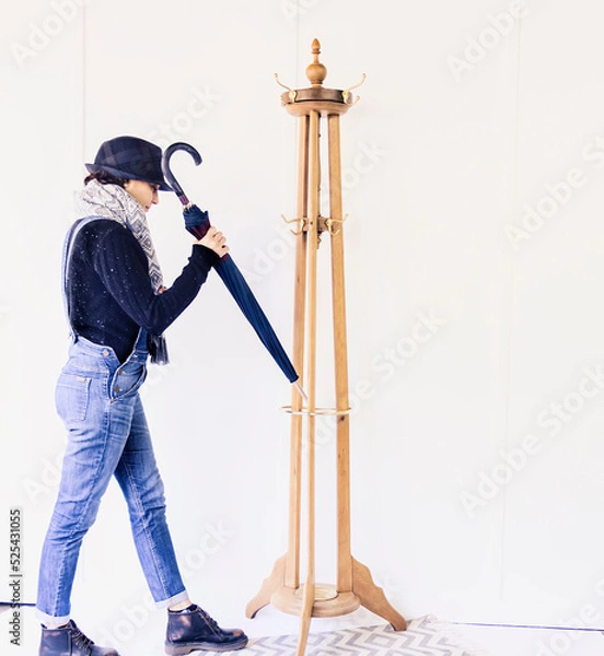 Obraz Portrait of a Caucasian woman next to a wooden coat rack hanging her umbrella
