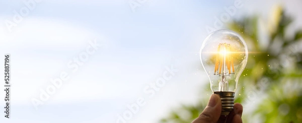 Fototapeta Hand holding a light bulb with light growing for renewable energy. creative ideas for save environment and sustainable. Eco energy concept. For web banner or web design.