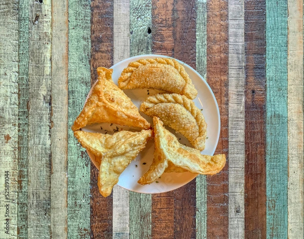 Fototapeta Creole empanadas and ham and cheese empanadas on a wooden background of colored boards.