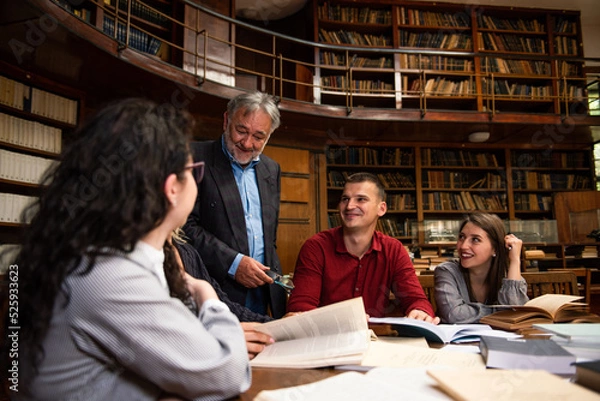 Fototapeta The senior professor gives a lecture to the students at the University library