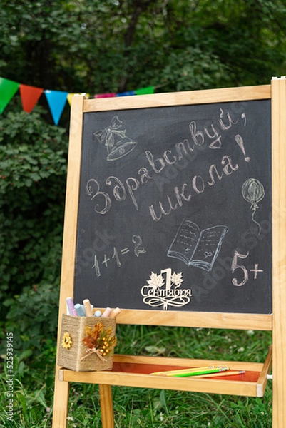 Fototapeta Back to school time. Greeting for russian Day of Knowledge. Blackboard chalk handwriting, translated Welcome to school. Hello, school. Batch of chulk. Selective focus.