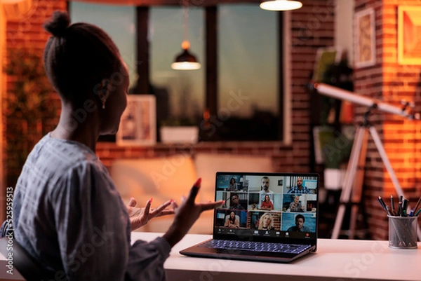 Fototapeta Corporate worker talking with remote team on business meeting using laptop, back view. Company colleagues brainstorming on teleconference, freelancing and telework concept