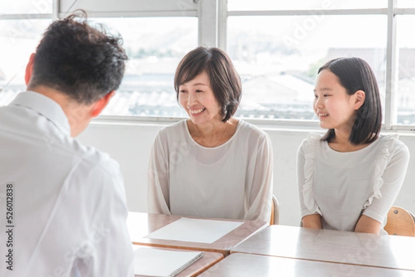 Fototapeta 教室で三者面談をする担任の先生と親子（進路相談）

