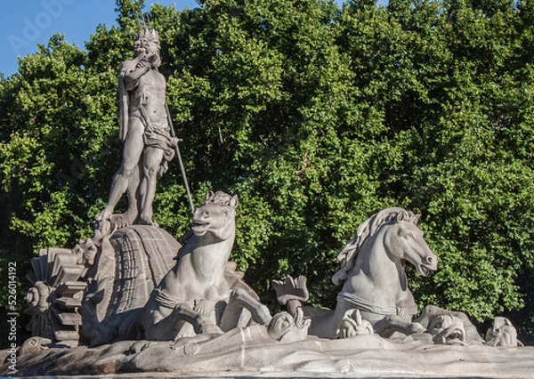 Fototapeta Fountain of Neptune in the old town of Madrid, Spain. The statue shows the god of the sea, with a trident in one hand and a coiled snake in the other, surrounded by dolphins and two sea horses.